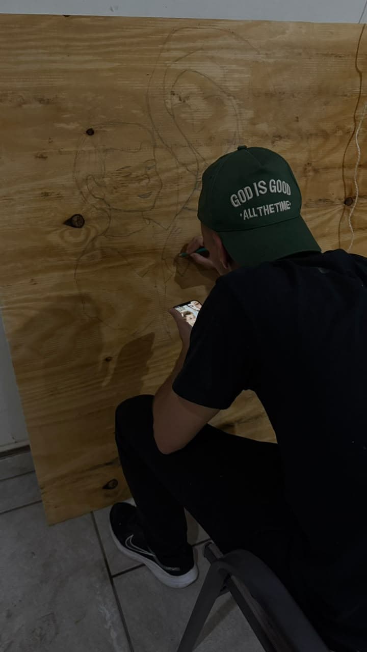 Un ilustrador trazando una imagen de la Virgen sobre madera